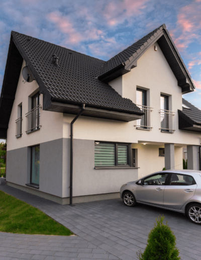A modern two-story house with a gray and white exterior and a car in the driveway.